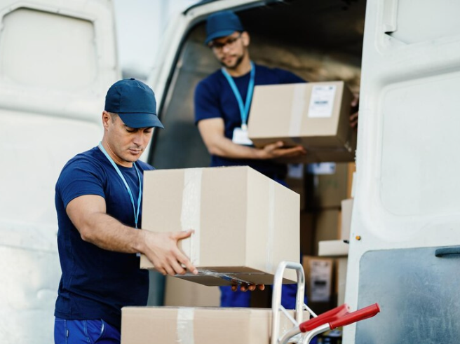 Two movers standing with boxes out of a van.
