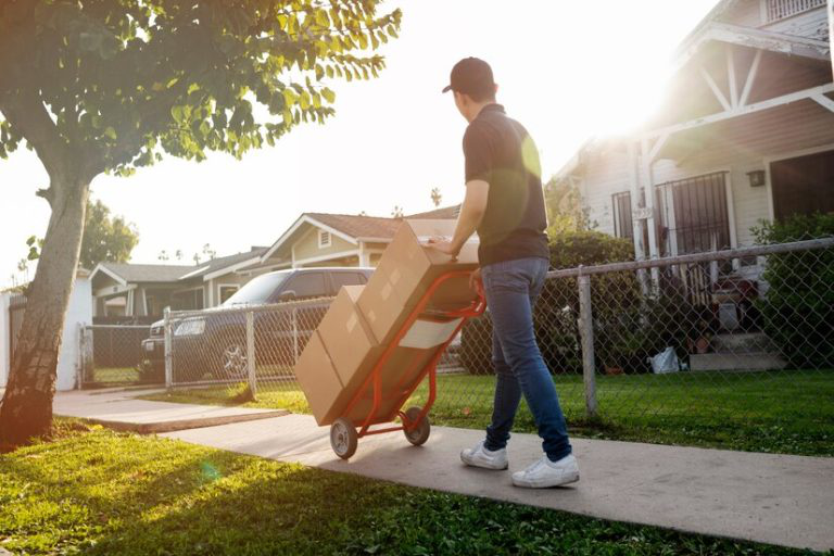 A commercial mover carrying out boxes on a driveway. 